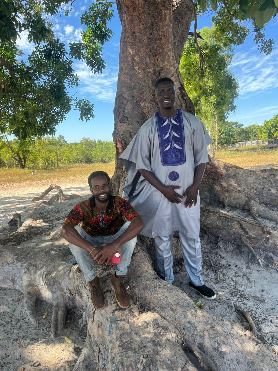 Two missionaries gathered at the base of a large baobab tree in Africa